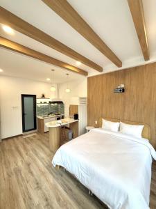 a bedroom with a large white bed and a kitchen at Chạm's Hotel & Homestay in Ho Chi Minh City