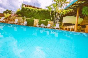 a large swimming pool with chairs and a hedge at Hotel Dom Otto in Vespasiano