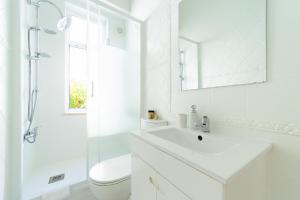 un bagno bianco con lavandino e WC di Peaceful 2-bedroom House with Garden at the heart of Benfica a Lisbona Altre 12 foto