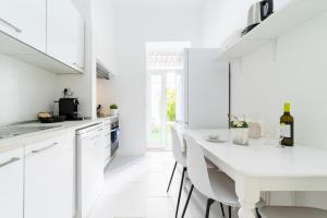 una cucina bianca con tavolo e sedie bianchi di Peaceful 2-bedroom House with Garden at the heart of Benfica a Lisbona