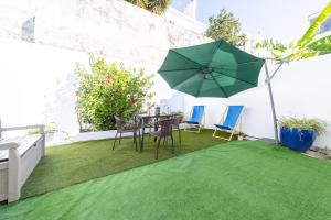 un tavolo e sedie con ombrellone su un prato di Peaceful 2-bedroom House with Garden at the heart of Benfica a Lisbona