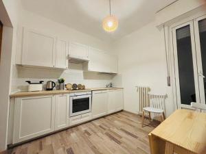 a kitchen with white cabinets and a wooden floor at NEW Brenta 10 minutes To Duomo M3-15 minutes to Linate - Full furnished APT with AC, Wi-fi and more in Milan