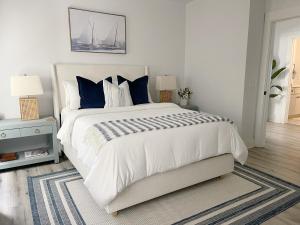 a bedroom with a large white bed with blue pillows at Elegant Duplex Steps to Forsyth! in Savannah