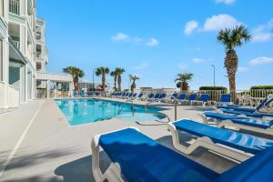 a swimming pool with blue lounge chairs and palm trees at Grand Caribbean 111 Beach View Condo pool views in Orange Beach