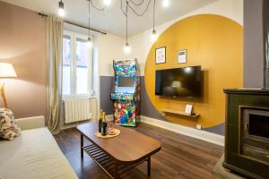 a living room with a couch and a tv and a table at Zenora Loft Hot Tub & Arcade in Downtown in Mulhouse