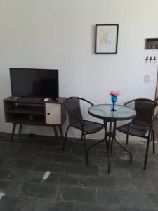 uma sala de estar com mesa, cadeiras e uma TV em Pousada Bertioga em Bertioga