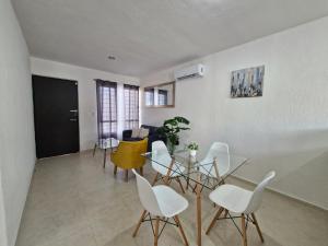 a dining room with white chairs and a glass table at Casa Izamal Mérida in Mérida