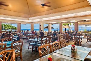 people sitting at tables in a restaurant with the ocean at Kaanapali Shores 309 in Honokowai