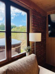 a room with a couch and a lamp and windows at Dobra Wola Dobra Chata - domek z balią w naturze in Dobra Wola