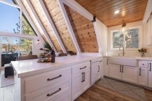 a kitchen with white cabinets and a wooden ceiling at Cove Lakeside Jacuzzi, Central AC, Stunning View in Big Bear Lake +128 photos
