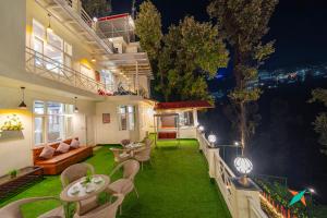 a house with a green yard with tables and chairs at Zostel Homes Mussoorie in Mussoorie
