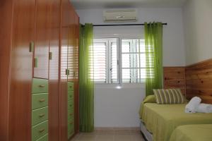 una camera da letto con tende verdi, un letto e una finestra di Memorable Holidays With Your Family a Maspalomas Altre 57 foto