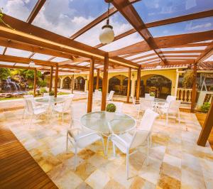 a patio with a glass table and white chairs at Hotel Dom Otto in Vespasiano