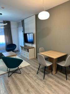 a living room with a table and chairs and a television at LUX APARTMENS GLIGA Lux 14 in Sombor