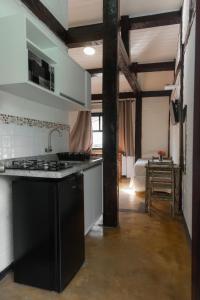 a kitchen with a sink and a stove in a room at Pousada Bellissima in Boicucanga