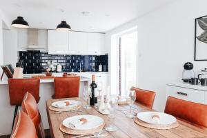 a kitchen with a wooden table with plates and wine glasses at The Coachhouse by Solace Stays in Bassaleg