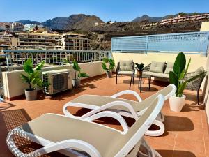 a balcony with chairs and tables on a building at Poseidon Dreams Tenerife in Puerto de Santiago