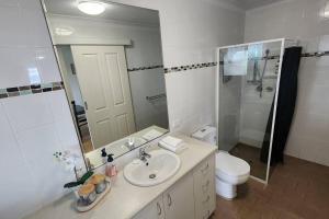 a bathroom with a sink and a toilet and a mirror at Cosy Bayside Studio in Esperance