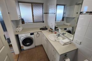 a bathroom with a sink and a washing machine at Cosy Bayside Studio in Esperance