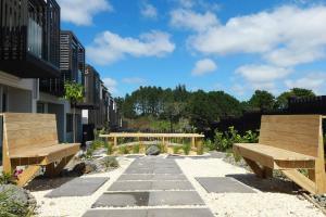 due panchine di legno sedute su una passerella di Cozy 2 Bedroom Waterview Home for Work and Family ad Auckland