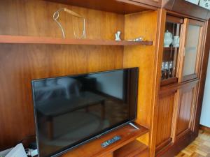 a flat screen tv in a wooden entertainment center at La terraza del Naranco - 3 habitaciones , PARKING y WIFI free in Oviedo