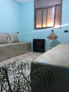 a bedroom with two beds and a television and a window at Dar Fatima in Aït Ali