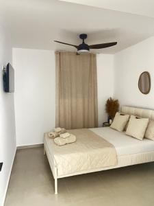 a white bedroom with a bed with a ceiling fan at Koselig Lodge in Pídhasos