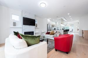 a living room with two white couches and a red chair at Luxury Home Near DT, New Build, High-End Features in Calgary