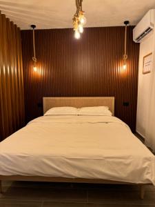 a bedroom with a white bed with a wooden wall at ZA Apartment in Korçë