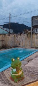 a frog toy sitting next to a swimming pool at Tia do Coco Recanto in Caraguatatuba