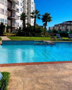 a swimming pool in front of a building with palm trees at Rosarito Sol y Mar Getaway in Rosarito Beach