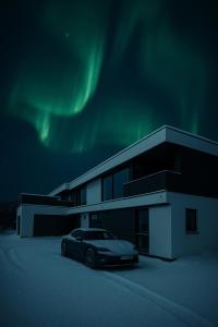 un'auto parcheggiata di fronte a un edificio sotto l'aurora boreale di Platinum VIP - Northern light luxury house a Tromsø