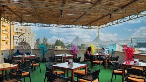 a restaurant with tables and chairs and a view of the pyramids at Hostalio Pyramid View in Cairo