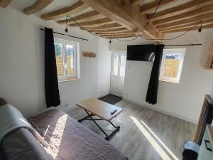 a room with a bed and a table and a refrigerator at Le Gîte d'Amoé in Mélamare