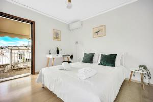 a white bedroom with a large bed and a window at Athens sky & Acropolis view rooftop apartment! in Athens
