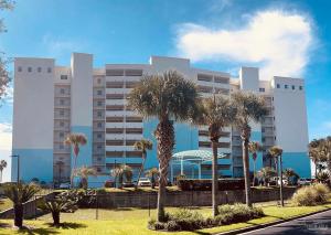 a large building with palm trees in front of it at Ocean Serenity - Ocean View in Pensacola