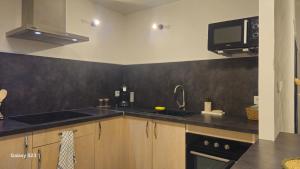 a kitchen with a sink and a microwave at Charmant T2 centre Montélimar in Montélimar