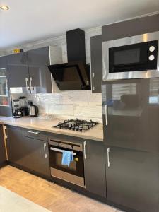 a kitchen with a stove and a microwave at Cosy bedroom near London City Airport in London
