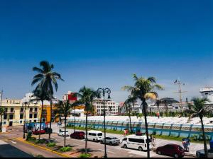 a parking lot with cars and palm trees and a building at Hotel Ruiz Milán in Veracruz