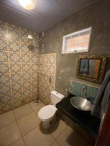 a bathroom with a toilet and a sink and a mirror at Quintal da prainha Bar - pousada simples-beira da lagoa in Santana do Riacho +47 photos