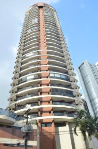 a tall building with a palm tree in front of it at Apartamento central para COP 30, próximo à estação das Docas in Belém