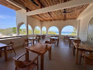 an empty restaurant with tables and chairs and windows at Segreto Boutique Resort in Gili Trawangan