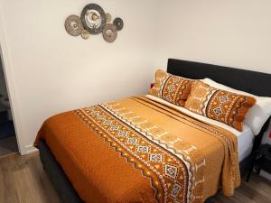 a bed with an orange blanket and pillows on it at Bright Escape Falls Retreat in Niagara Falls