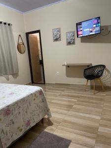 a bedroom with a bed and a desk and a television at Hotel Real Ipiranga in Três Marias