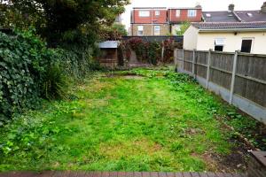 a yard with green grass next to a fence at Shelters En-suite Entire House in Seven Kings