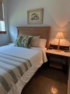 ein Schlafzimmer mit einem Bett und einem Tisch mit einer Lampe in der Unterkunft Whispering Pines Retreat, Secluded Cabin with Hot Tub & Pond in Jacksonville