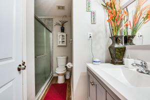 a bathroom with a toilet and a sink and a vase with flowers at 9 Mi to Downtown Atlanta Home with Deck and Yard! in Tolliver Heights +19 photos