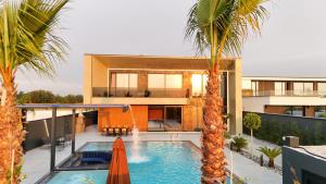 a house with a swimming pool and two palm trees at Bliss Luxury Villa in Rrushkull