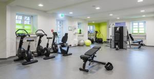 einen Fitnessraum mit mehreren Laufbändern und Heimtrainern in der Unterkunft Kardinal Schulte Haus in Bergisch Gladbach