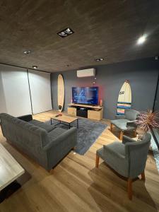 Una sala de estar con un sofá y dos sillas y un televisor. en Casa las lomas, en Miramar